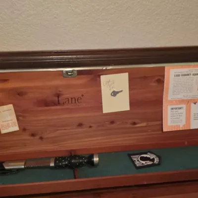 Interior lid of a vintage Lane cedar chest featuring original branding, paperwork, key, and felt-lined tray storage.