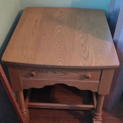 Traditional oak accent side table featuring a single drawer with double knobs and turned legs with lower stretchers.