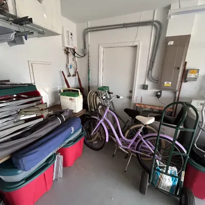 Electra Townie lavender cruiser bicycle alongside various garage items including plastic storage totes, a hand truck, folding lawn...