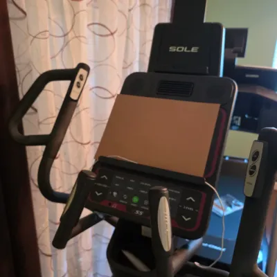 Sole Fitness E25 elliptical machine console featuring handle controls and a media ledge with a tablet holder.
