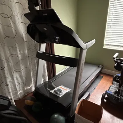 Pro-Form motorized treadmill with an integrated display screen, presented alongside several weighted medicine balls.