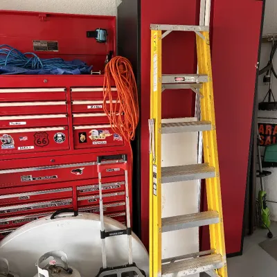 Workshop storage setup featuring a large red Craftsman rolling tool chest, a NewAge Products red and black metal cabinet, and a yellow...