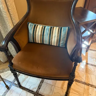Sale Photo Thumbnail #58: Vintage dark wood barrel-back armchair featuring brown upholstery and turned legs, styled with a striped lumbar pillow.