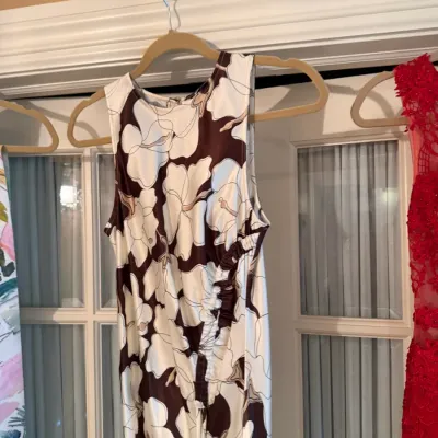 Sale Photo Thumbnail #110: Sleeveless maxi dress featuring a bold brown and white floral pattern with side ruched detailing, displayed on a hanger.