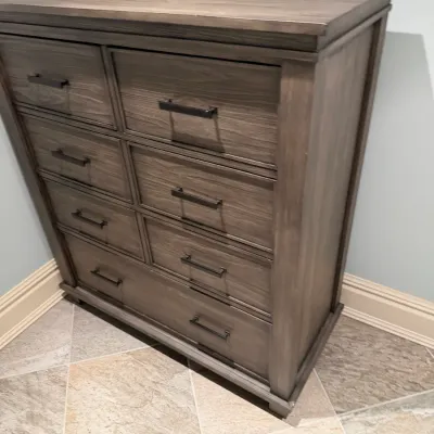 Sale Photo Thumbnail #142: Modern weathered gray wood chest of drawers with black bar handles. It features eight drawers of varying sizes and appears to be in clean, lightly used condition.