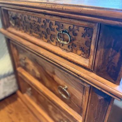 Sale Photo Thumbnail #83: Traditional wooden nightstand featuring three drawers, brass drop-ring handles, and intricate carved scrolling details on the top drawer front.