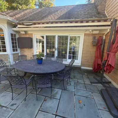 Sale Photo Thumbnail #19: Large cast aluminum patio dining set featuring a round lattice-top table and eight matching armchairs, paired with cantilevered red patio umbrellas.