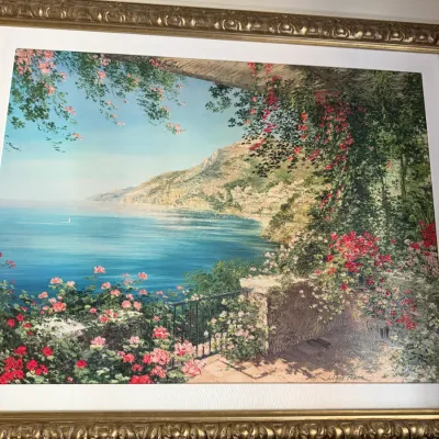 Sale Photo Thumbnail #70: Large framed Mediterranean coastal art print by Liliana Frasca, featuring a vibrant terrace view of the sea and floral foliage in an ornate gilded frame.