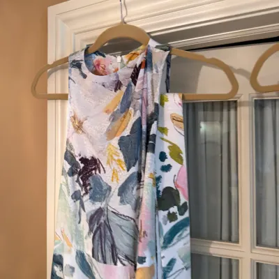 Sale Photo Thumbnail #111: Sleeveless floral print dress featuring an abstract watercolor design in shades of blue, pink, and yellow, displayed on a beige velvet hanger.