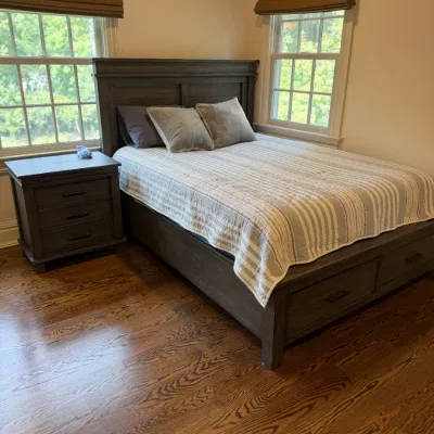 Sale Photo Thumbnail #145: Modern dark gray wooden bed frame with built-in footboard storage drawers, paired with a matching three-drawer nightstand.