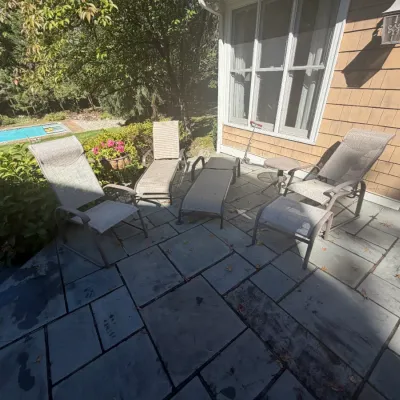Sale Photo Thumbnail #23: Set of outdoor patio furniture including mesh reclining lounge chairs, armchairs with footrests, and a small side table arranged on a stone patio.