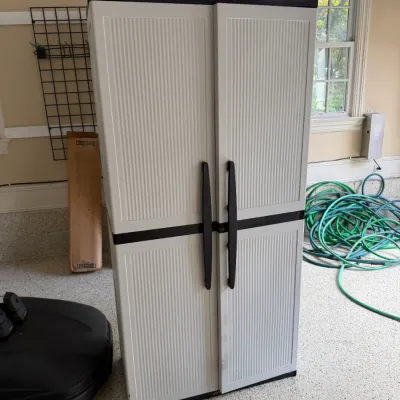 Sale Photo Thumbnail #126: Tall, light gray and black plastic storage cabinet with double doors and vertical ribbed paneling.