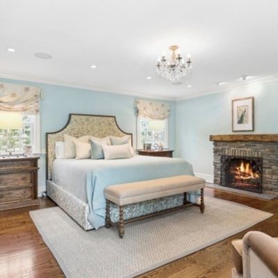 Sale Photo Thumbnail #8: Spacious bedroom suite featuring an upholstered king-size bed, a wooden end-of-bed bench, matching nightstands, and a stone-clad fireplace.