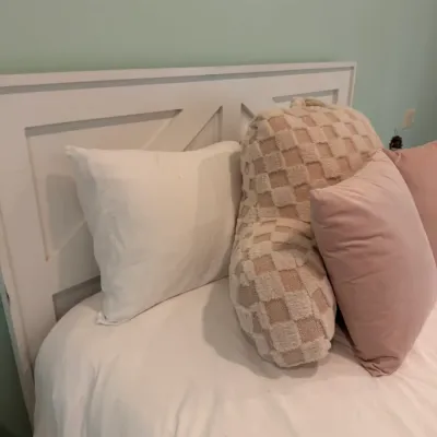 Sale Photo Thumbnail #169: White modern farmhouse-style wooden headboard with an assortment of decorative accent pillows and a backrest pillow.
