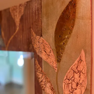Sale Photo Thumbnail #158: Close-up detail of a decorative framed mirror featuring an artisan mixed-media leaf motif with metallic and textured elements.