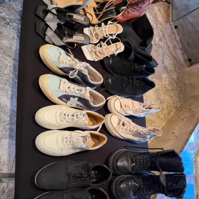 Sale Photo Thumbnail #99: Large assortment of women's shoes and boots, including designer heels, sneakers, and leather combat boots arranged on a table.