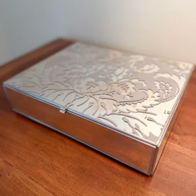 Sale Photo Thumbnail #94: Rectangular mirrored jewelry or trinket box with an etched damask floral lid pattern and silver-toned trim.