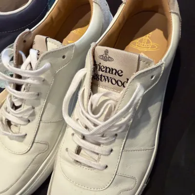 Sale Photo Thumbnail #101: Pair of Vivienne Westwood white leather low-top sneakers featuring branded tongue labels and gold orb insoles.
