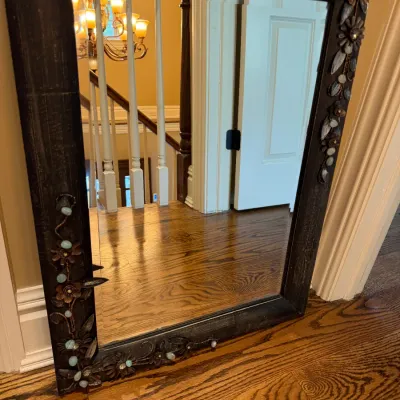 Sale Photo Thumbnail #143: Dark wooden framed wall mirror featuring applied metal floral vines and stone embellishments around the perimeter.
