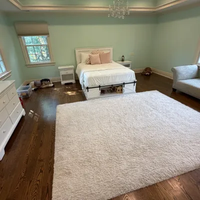 Sale Photo Thumbnail #159: Spacious bedroom suite featuring a white wooden bed frame with under-bed storage, a matching double dresser, nightstands, a large plush area rug, and a upholstered chaise lounge.