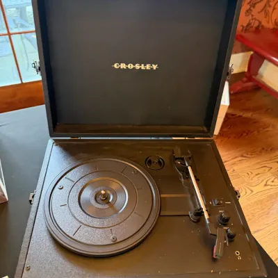 Sale Photo Thumbnail #120: Crosley suitcase-style turntable record player in black leatherette casing with built-in speakers.