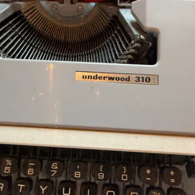 Sale Photo Thumbnail #124: Vintage Underwood 310 portable manual typewriter in light blue with black keys, showing dust and light wear from use.