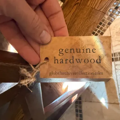 Sale Photo Thumbnail #65: A manufacturer tag reading "genuine hardwood" from Global Archive Collection attached to a piece of dark wood furniture.