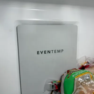 Sale Photo Thumbnail #132: Interior view of a modern refrigerator showing the EvenTemp cooling vent panel and a wire rack holding packaged food.