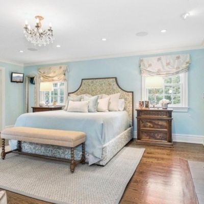 Sale Photo Thumbnail #7: Spacious primary bedroom suite featuring a king-size upholstered bed, matching nightstands, a stone fireplace, and a small crystal chandelier.