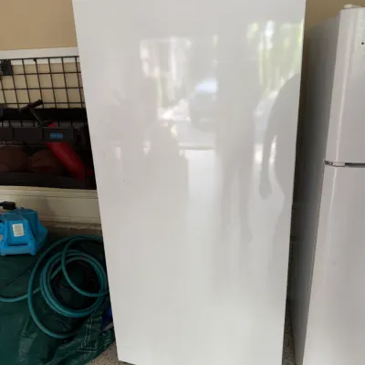 Sale Photo Thumbnail #130: White Frigidaire upright freezer sitting next to a refrigerator in a garage, featuring a smooth finish and wire top storage basket.