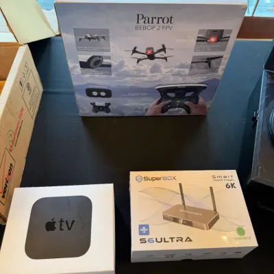 Sale Photo Thumbnail #121: Collection of boxed electronics including a Parrot Bebop 2 FPV drone kit, an Apple TV 4K, and a SuperBOX S6 Ultra Smart Media Player.