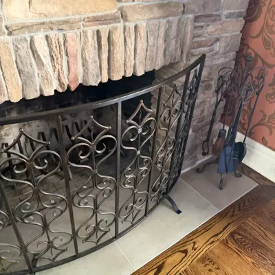 Sale Photo Thumbnail #69: Curved wrought iron fireplace screen with decorative scrollwork alongside a matching iron tool set.