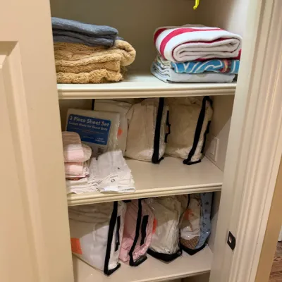 Sale Photo Thumbnail #156: Linen closet filled with assorted bedding and towels, including packaged sheet sets, folded bath towels, and blankets.