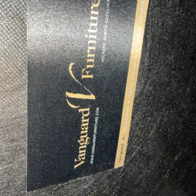Sale Photo Thumbnail #63: Manufacturer tag for Vanguard Furniture, located in Hickory, North Carolina, attached to dark upholstered fabric.
