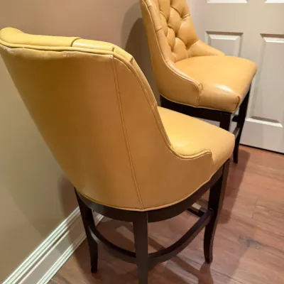 Sale Photo Thumbnail #141: Pair of contemporary leather barstools featuring mustard yellow button-tufted upholstery and dark wood legs.
