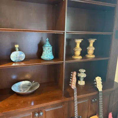 Sale Photo Thumbnail #50: Large dark wood wall unit with open shelving and lower storage cabinets, displaying decorative objects alongside various acoustic and electric guitars.