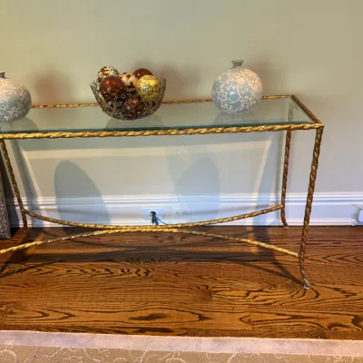 Sale Photo Thumbnail #35: Gilt metal console table featuring a glass top and twisted rope-style frame with cross-stretcher base, styled with ceramic vases and a decorative bowl.