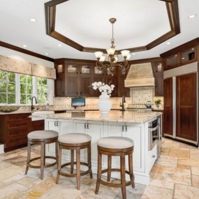 Sale Photo Thumbnail #5: Set of three round wooden kitchen bar stools with upholstered seats, arranged at a white island inside a spacious luxury kitchen.