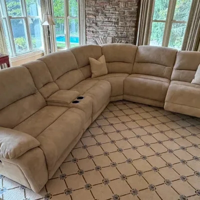 Sale Photo Thumbnail #178: Large contemporary tan microfiber curved sectional sofa featuring reclining seats, built-in cup holders, a storage console, and matching accent pillows.