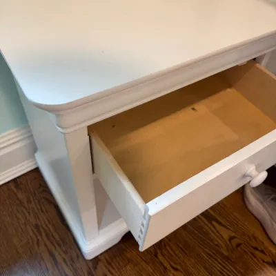 Sale Photo Thumbnail #196: White painted wooden nightstand with an open top drawer showing dovetail construction.