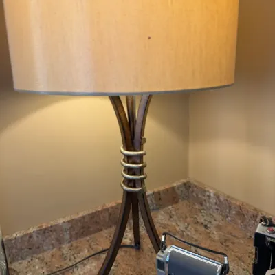 Sale Photo Thumbnail #193: Modern table lamp featuring a flared tripod base with silver metallic ring accents and a beige drum shade.