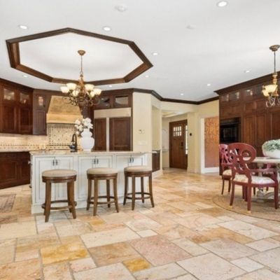 Sale Photo Thumbnail #6: Spacious kitchen and dining area featuring dark wood cabinetry, an island with barstools, and a round dining set with red carved chairs.