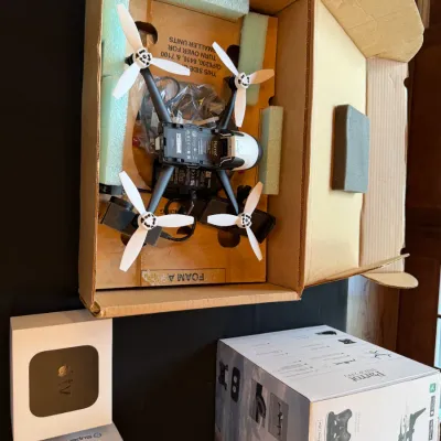 Sale Photo Thumbnail #122: Parrot Bebop 2 quadcopter drone in its original packaging, accompanied by its retail box, an Apple TV device in box, and a SuperBox S6 Ultra box.