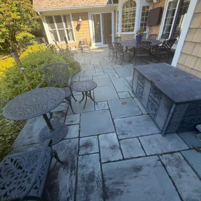 Sale Photo Thumbnail #16: Outdoor stone patio featuring black cast aluminum bistro sets, side tables, a storage bench, and a larger dining set in the background.
