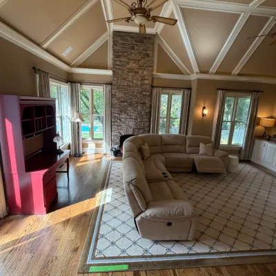 Sale Photo Thumbnail #177: Spacious living room featuring a tan upholstered sectional sofa, a large patterned area rug, and a red painted desk with a top hutch.