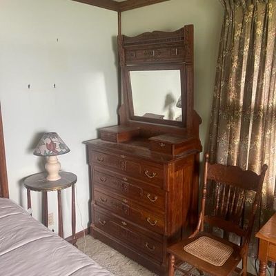 Sale Photo Thumbnail #25: Antique Eastlake-style carved oak chest of drawers with an attached mirror and trinket drawers, paired with a cane-seat wooden side chair.