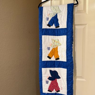 Sale Photo Thumbnail #50: Handmade appliqued quilt featuring Sunbonnet Sue/Overall Sam fishing motifs with a blue border, hanging on a door frame.