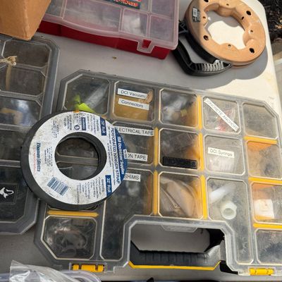 Sale Photo Thumbnail #91: Assorted hardware and organization supplies, including a yellow multi-compartment portable storage case, a roll of Thomas & Betts electrical tape, and additional small parts organizers.