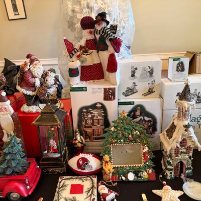 Sale Photo Thumbnail #7: Collection of Christmas decorations including Department 56 village boxes, fabric snowman figures, Santa figurines, a red truck table piece, and decorative ornaments.