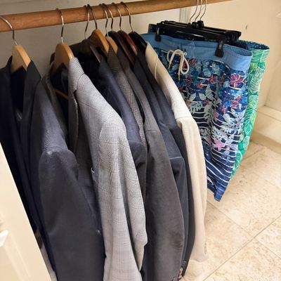 Sale Photo Thumbnail #24: Collection of men's clothing hanging in a closet, including several suit jackets, blazers, and printed swim trunks.